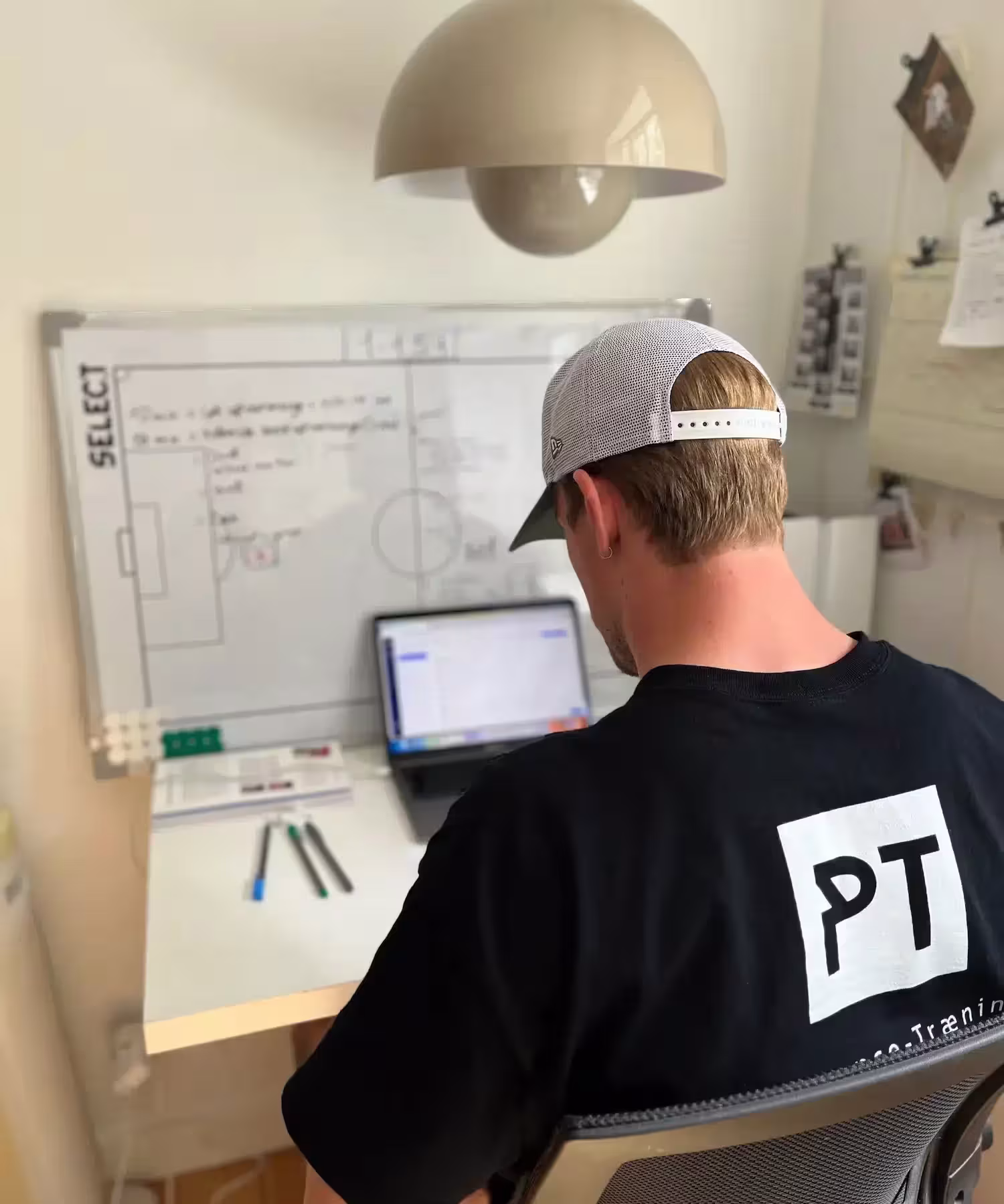 Alexander Brix sidder ved skrivebord iført trøje med Performance Træning logo