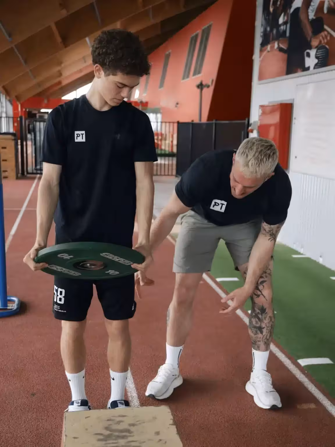 fysisk træner instruerer ung fodboldspiller i styrketræning med vægtløftning